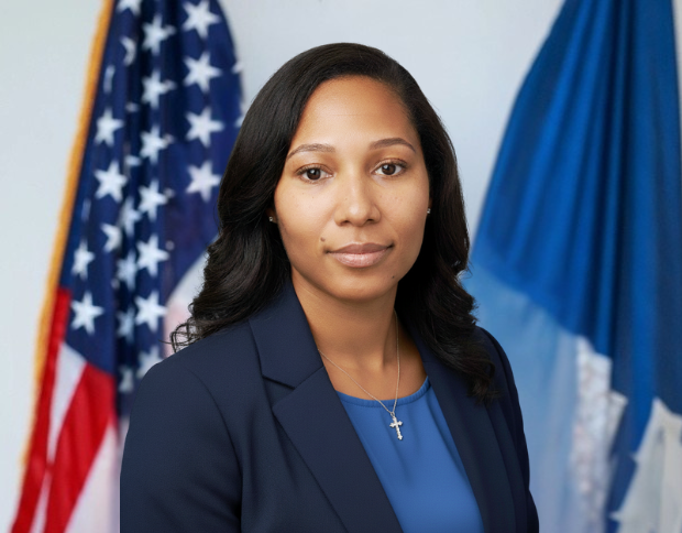 Portrait of Dana Casbon, Special Assistant to the Executive Director, wearing a navy blue blazer and a cross necklace.