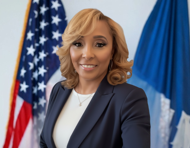 Portrait of Harrolynn Sherman, Human Resources Manager, smiling in a navy blazer with the American flag in the background.