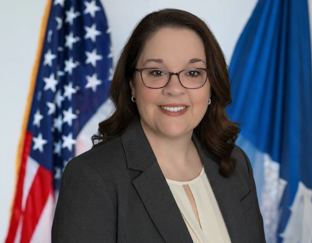 Portrait of Melissa Morel, Accounting Clerk, smiling in a dark grey suit and glasses.