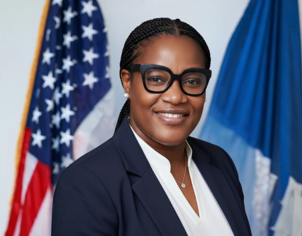 Portrait of Shawna Williams, Purchasing Agent, smiling in a navy suit and wearing large black glasses.